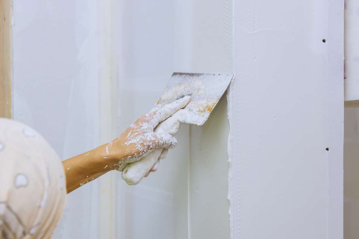 Male builder repairs wall with a spatula plaster on a wall