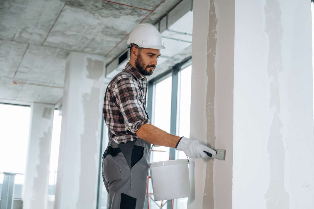 Puttying the wall. A man is renovating an unfinished room.