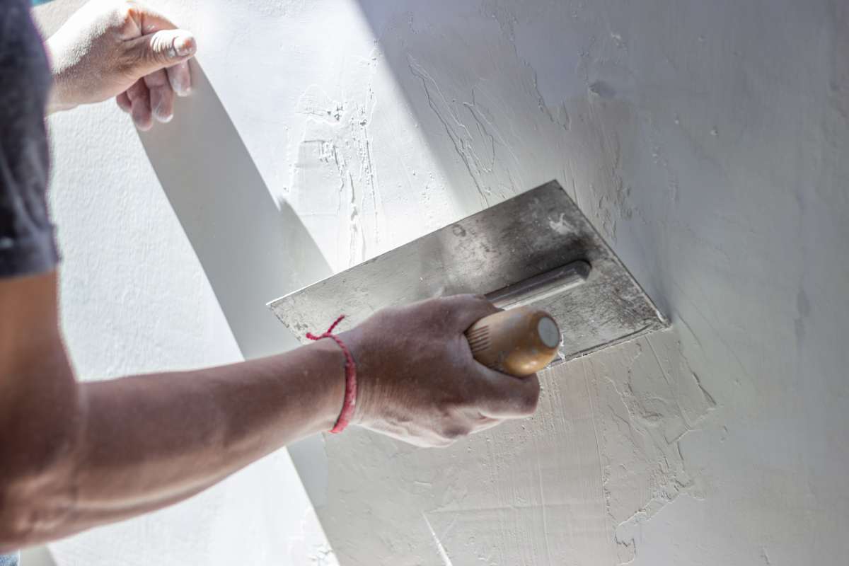 Construction worker skillfully applies plaster to a wall using a trowel, creating a smooth surface during a home renovation or construction project